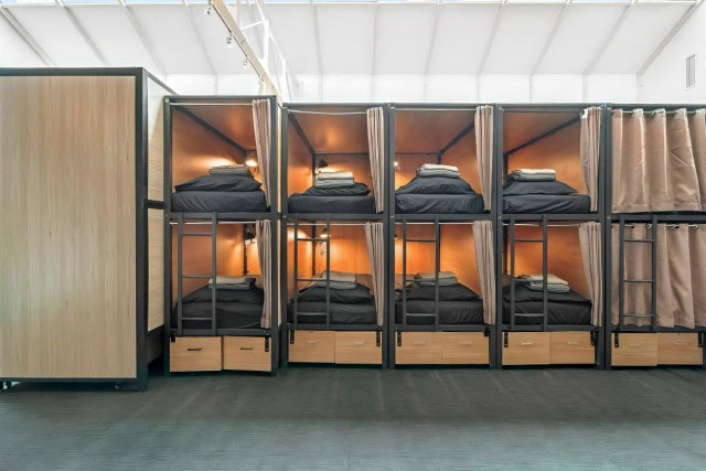 Capsule pod beds in a Gold Coast hostel with privacy curtains and lights